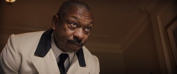 Movie still from “Indiana Jones and the Dial of Destiny” (2023), directed by James Mangold – A man with a mustache and a white suit and black tie; Close Up shot, Low angle