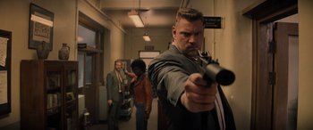 Movie still from “Indiana Jones and the Dial of Destiny” (2023), directed by James Mangold – A man holding a gun in front of two other people; Medium shot, Low angle