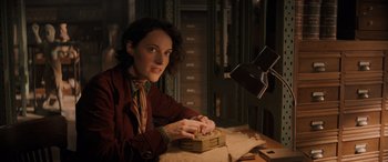 Movie still from “Indiana Jones and the Dial of Destiny” (2023), directed by James Mangold – A woman sitting at a table with a box; Medium shot, Low angle