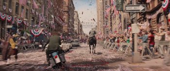 Movie still from “Indiana Jones and the Dial of Destiny” (2023), directed by James Mangold – A person riding a horse down a street; Wide shot, High angle