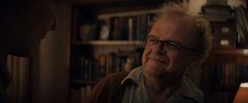 Movie still from “Indiana Jones and the Dial of Destiny” (2023), directed by James Mangold – An older man wearing glasses sitting in front of a book shelf; Close Up shot, Over the shoulder angle