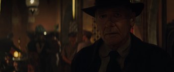 Movie still from “Indiana Jones and the Dial of Destiny” (2023), directed by James Mangold – An old man wearing a hat and a tie; Close Up shot, Over the shoulder angle