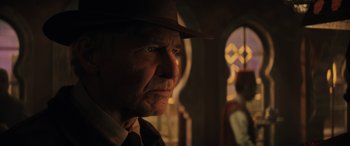 Movie still from “Indiana Jones and the Dial of Destiny” (2023), directed by James Mangold – An older man wearing a hat and a tie; Close Up shot, Over the shoulder angle