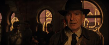 Movie still from “Indiana Jones and the Dial of Destiny” (2023), directed by James Mangold – An old man wearing a hat and a tie; Close Up shot, Over the shoulder angle