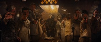Movie still from “Indiana Jones and the Dial of Destiny” (2023), directed by James Mangold – A group of people standing around a table with a cake on it; Wide shot, Low angle