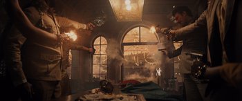 Movie still from “Indiana Jones and the Dial of Destiny” (2023), directed by James Mangold – A group of people holding guns in a room; Wide shot, Low angle