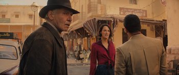 Movie still from “Indiana Jones and the Dial of Destiny” (2023), directed by James Mangold – A group of people standing on the side of the street; Medium shot, Over the shoulder angle
