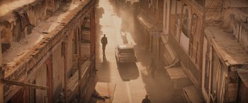 Movie still from “Indiana Jones and the Dial of Destiny” (2023), directed by James Mangold – A man riding a bike down a street next to a car; Extreme Wide shot, High angle