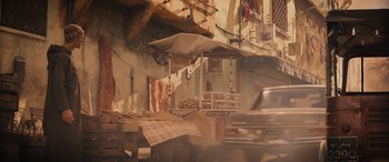 Movie still from “Indiana Jones and the Dial of Destiny” (2023), directed by James Mangold – An outdoor market in a city with a car passing by; Wide shot, Over the shoulder angle