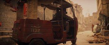 Movie still from “Indiana Jones and the Dial of Destiny” (2023), directed by James Mangold – A man driving a small red car down a street; Wide shot, High angle