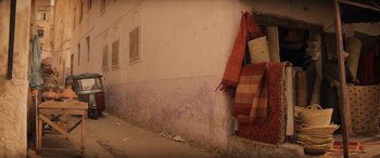 Movie still from “Indiana Jones and the Dial of Destiny” (2023), directed by James Mangold – An orange and white rug hanging on a wall; Wide shot, High angle