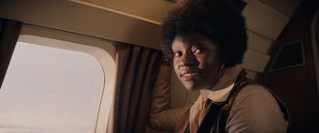 Movie still from “Indiana Jones and the Dial of Destiny” (2023), directed by James Mangold – A man with a black afro is looking out a window; Close Up shot, Low angle
