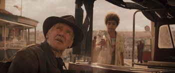 Movie still from “Indiana Jones and the Dial of Destiny” (2023), directed by James Mangold – An older man and a young man are standing next to each other; Medium shot, Over the shoulder angle