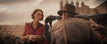 Movie still from “Indiana Jones and the Dial of Destiny” (2023), directed by James Mangold – A woman standing next to a man wearing a hat; Medium shot, Over the shoulder angle