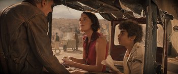 Movie still from “Indiana Jones and the Dial of Destiny” (2023), directed by James Mangold – A woman sitting in a vehicle with a man standing next to her; Medium shot, Over the shoulder angle