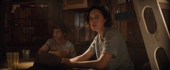 Movie still from “Indiana Jones and the Dial of Destiny” (2023), directed by James Mangold – Two young people sitting at a table in a room; Medium shot, Over the shoulder angle