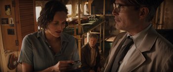 Movie still from “Indiana Jones and the Dial of Destiny” (2023), directed by James Mangold – A man and a woman looking at a cell phone in front of another man; Medium shot, Over the shoulder angle