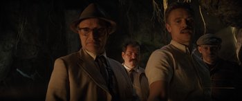 Movie still from “Indiana Jones and the Dial of Destiny” (2023), directed by James Mangold – A group of men standing next to each other in a dark room; Medium shot, Low angle