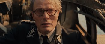 Movie still from “Indiana Jones and the Dial of Destiny” (2023), directed by James Mangold – A person wearing glasses and a uniform; Close Up shot, Over the shoulder angle