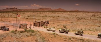 Movie still from “Indiana Jones and the Kingdom of the Crystal Skull” (2008), directed by Steven Spielberg – An old car is driving down the road near an old truck; Extreme Wide shot, High angle