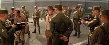 Movie still from “Indiana Jones and the Kingdom of the Crystal Skull” (2008), directed by Steven Spielberg – A group of men standing next to each other on a street; Medium shot, Over the shoulder angle