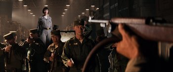 Movie still from “Indiana Jones and the Kingdom of the Crystal Skull” (2008), directed by Steven Spielberg – A group of men standing next to each other in a building; Medium shot, Over the shoulder angle