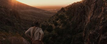 Movie still from “Indiana Jones and the Kingdom of the Crystal Skull” (2008), directed by Steven Spielberg – A man standing on top of a mountain looking at the sunset; Extreme Wide shot, High angle