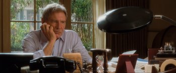 Movie still from “Indiana Jones and the Kingdom of the Crystal Skull” (2008), directed by Steven Spielberg – A man sitting at a table with a glass of water; Close Up shot, Low angle