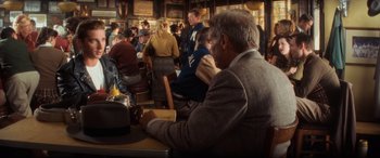 Movie still from “Indiana Jones and the Kingdom of the Crystal Skull” (2008), directed by Steven Spielberg – A man sitting at a table in a crowded restaurant; Medium shot, Over the shoulder angle