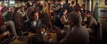 Movie still from “Indiana Jones and the Kingdom of the Crystal Skull” (2008), directed by Steven Spielberg – A group of people sitting at a table with drinks; Medium shot, Over the shoulder angle