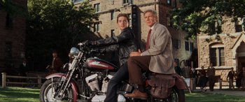 Movie still from “Indiana Jones and the Kingdom of the Crystal Skull” (2008), directed by Steven Spielberg – A man sitting on the back of a motorcycle next to another man; Medium shot, Low angle