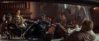 Movie still from “Indiana Jones and the Kingdom of the Crystal Skull” (2008), directed by Steven Spielberg – A group of people sitting in a room with a motorcycle; Wide shot, High angle