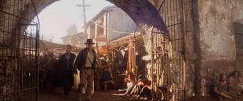 Movie still from “Indiana Jones and the Kingdom of the Crystal Skull” (2008), directed by Steven Spielberg – A man in a hat is walking through a market; Wide shot, Low angle