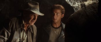 Movie still from “Indiana Jones and the Kingdom of the Crystal Skull” (2008), directed by Steven Spielberg – A man in a fedora and a leather jacket standing next to an older man in a hat; Close Up shot, Over the shoulder angle