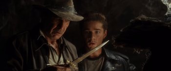 Movie still from “Indiana Jones and the Kingdom of the Crystal Skull” (2008), directed by Steven Spielberg – A man holding a knife next to an older man; Close Up shot, Over the shoulder angle