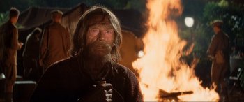 Movie still from “Indiana Jones and the Kingdom of the Crystal Skull” (2008), directed by Steven Spielberg – An old man with a long beard is standing in front of a fire; Medium shot, Low angle