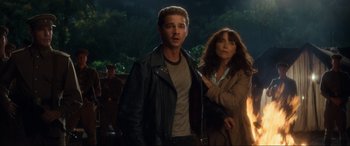 Movie still from “Indiana Jones and the Kingdom of the Crystal Skull” (2008), directed by Steven Spielberg – A man and a woman standing next to each other in front of trees; Medium shot, Low angle