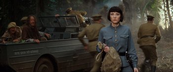 Movie still from “Indiana Jones and the Kingdom of the Crystal Skull” (2008), directed by Steven Spielberg – A woman in a military uniform holding a bag in front of an armored vehicle; Medium shot, Low angle