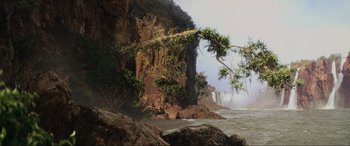 Movie still from “Indiana Jones and the Kingdom of the Crystal Skull” (2008), directed by Steven Spielberg – A cliff with trees growing out of it next to a body of water; Extreme Wide shot, Low angle