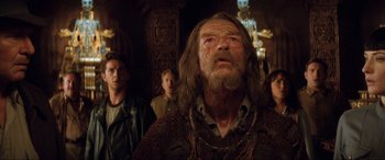 Movie still from “Indiana Jones and the Kingdom of the Crystal Skull” (2008), directed by Steven Spielberg – A group of people standing around a man with long hair; Close Up shot, Low angle