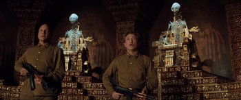 Movie still from “Indiana Jones and the Kingdom of the Crystal Skull” (2008), directed by Steven Spielberg – A man holding a gun while standing in a room; Medium shot, Low angle
