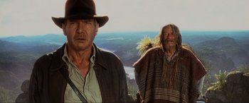 Movie still from “Indiana Jones and the Kingdom of the Crystal Skull” (2008), directed by Steven Spielberg – Two men standing on a hill with mountains in the background; Medium shot, Low angle