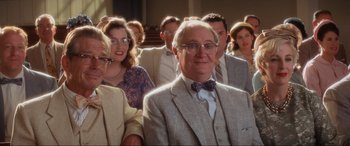Movie still from “Indiana Jones and the Kingdom of the Crystal Skull” (2008), directed by Steven Spielberg – An older man wearing a suit and bow tie in front of a group of people; Medium shot, Low angle