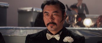 Movie still from “Indiana Jones and the Temple of Doom” (1984), directed by Steven Spielberg – A person wearing a suit and a bow tie; Close Up shot, Low angle