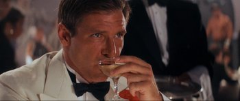 Movie still from “Indiana Jones and the Temple of Doom” (1984), directed by Steven Spielberg – A person holding a glass of wine; Close Up shot, Low angle