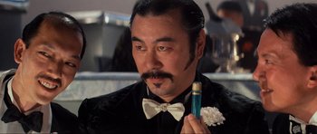 Movie still from “Indiana Jones and the Temple of Doom” (1984), directed by Steven Spielberg – A person wearing a bow tie; Close Up shot, Over the shoulder angle