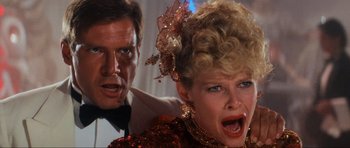 Movie still from “Indiana Jones and the Temple of Doom” (1984), directed by Steven Spielberg – A man and a woman in a red sequined dress; Close Up shot, Over the shoulder angle