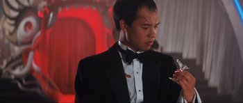 Movie still from “Indiana Jones and the Temple of Doom” (1984), directed by Steven Spielberg – A man in a tuxedo is holding something in his hand; Close Up shot, Low angle