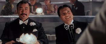 Movie still from “Indiana Jones and the Temple of Doom” (1984), directed by Steven Spielberg – A man in a suit and bow tie smiling for the camera; Medium shot, Low angle