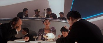 Movie still from “Indiana Jones and the Temple of Doom” (1984), directed by Steven Spielberg – A group of people sitting at a table with a cake on top of it; Medium shot, Low angle